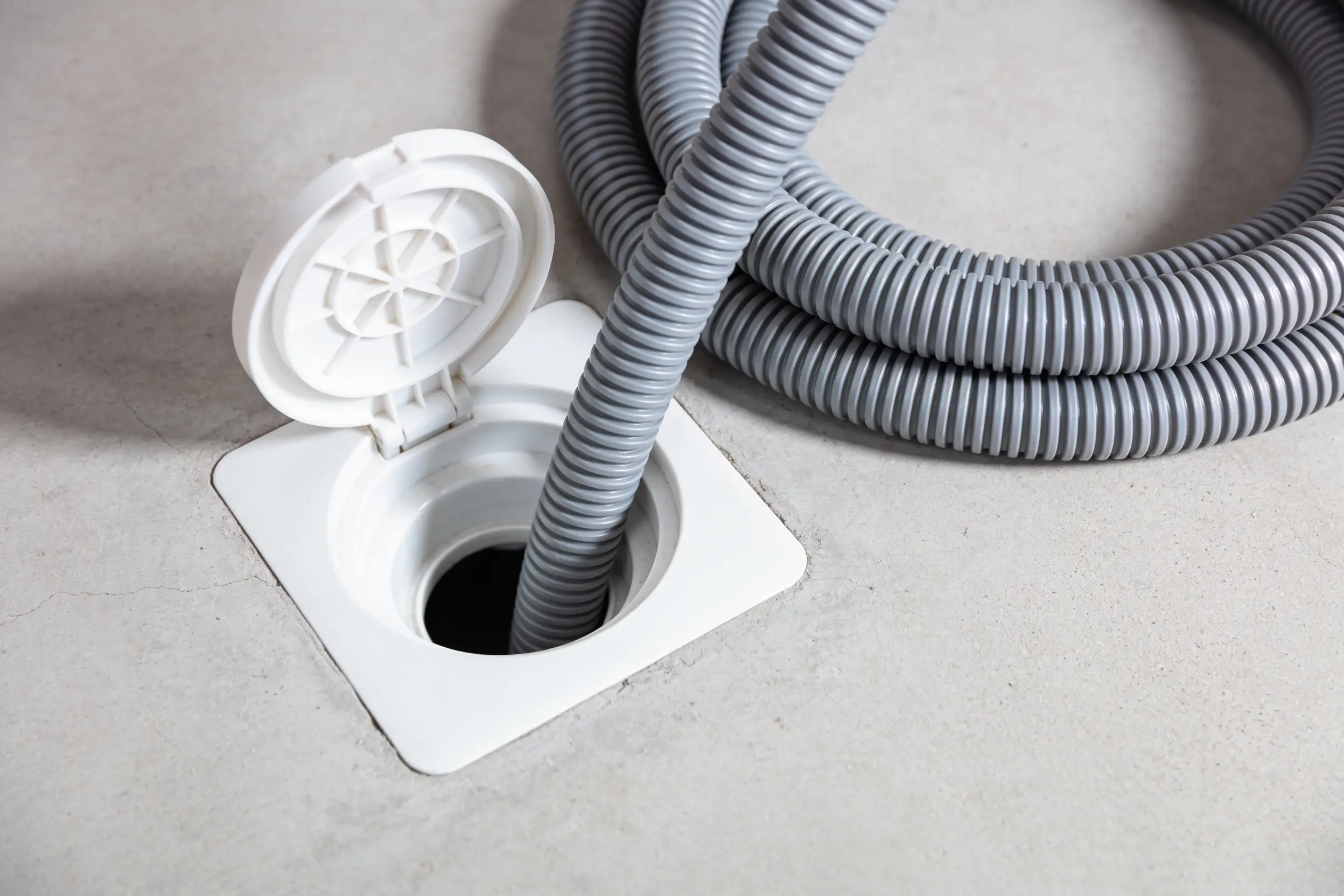 Drain auger cable feeding into an open floor level cleanout fitting