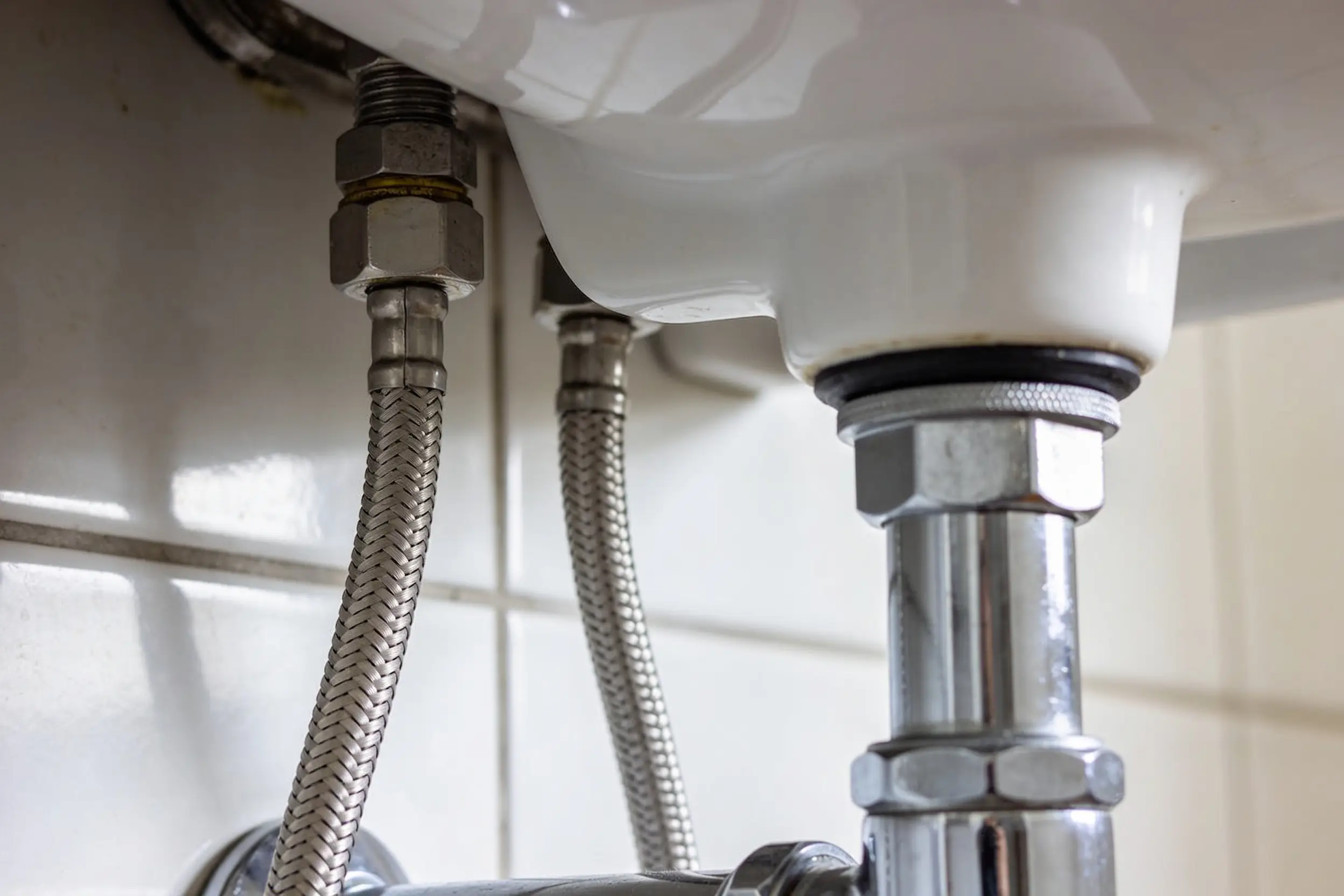 Chrome basin tap and its supply connections seen from below during installation